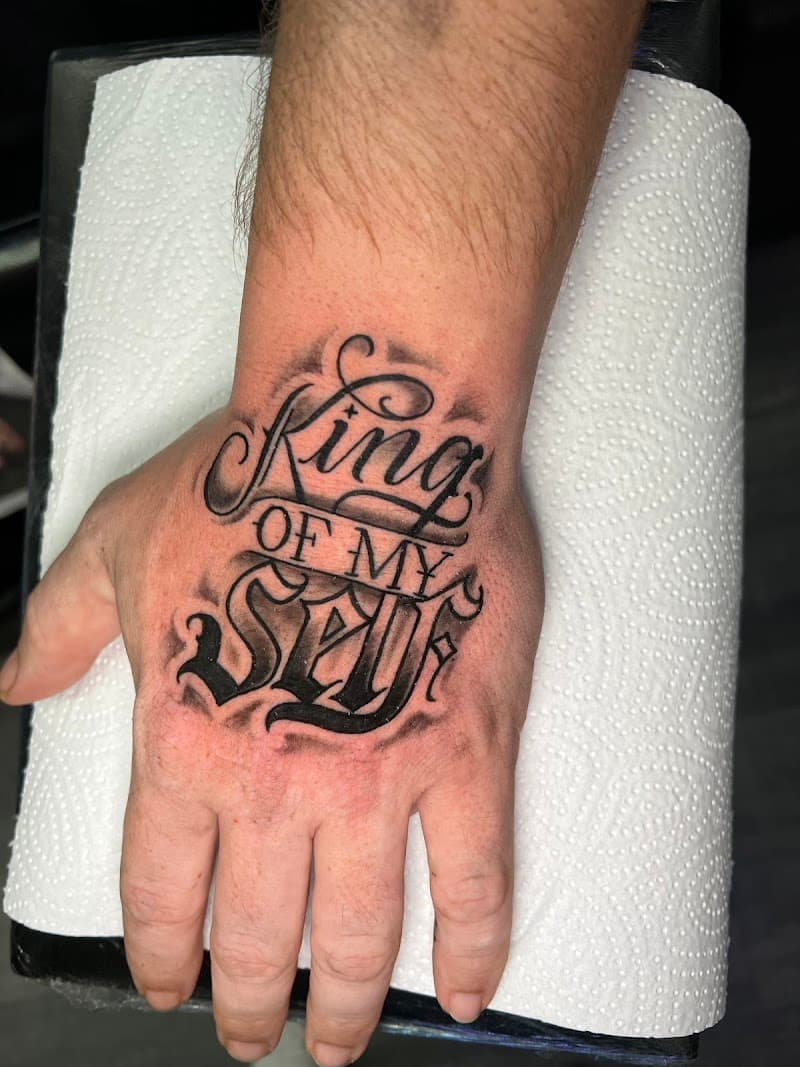 Sierlijke 'King of my Self' tekst tattoo op de hand.