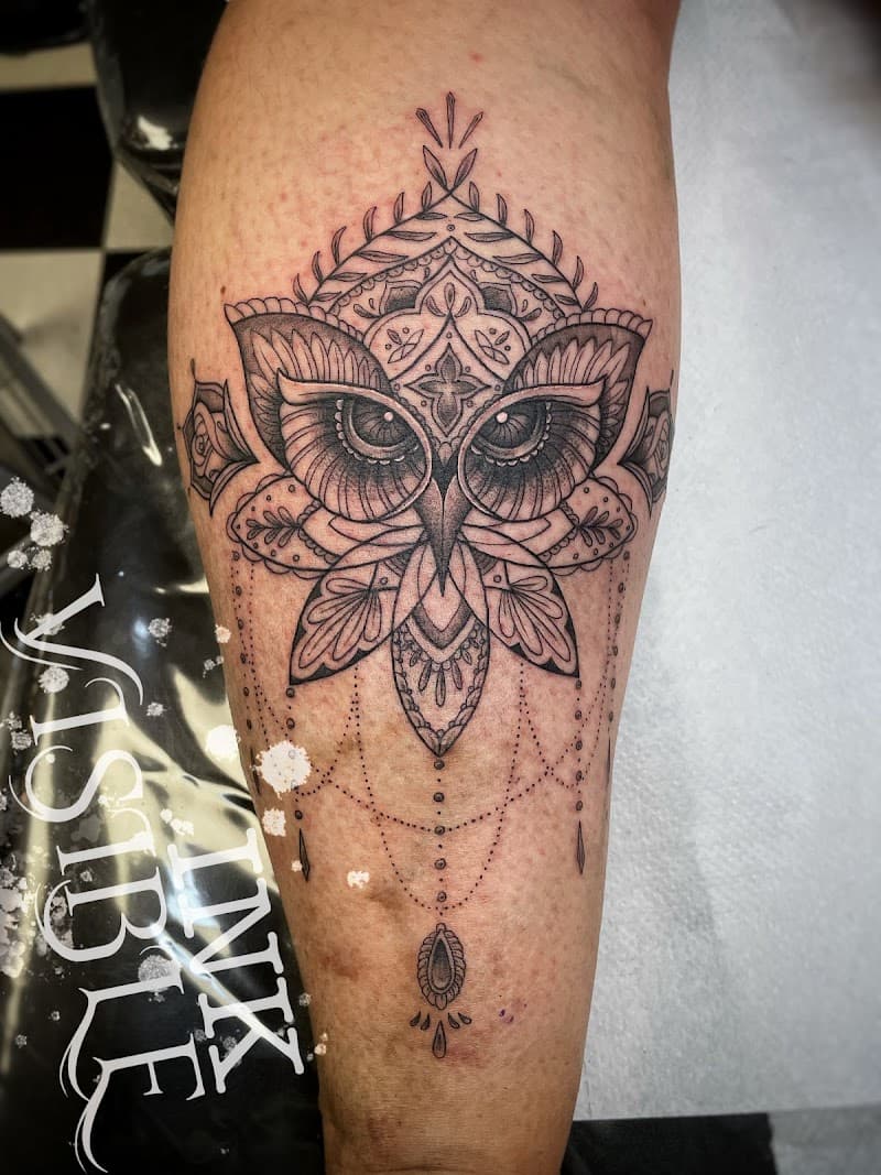 Zwart-wit ornamentele uil tattoo met mandala en dotwork op het onderbeen.