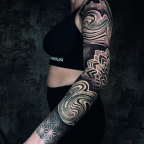 Geometrische en mandala sleeve tattoo met golvende patronen.