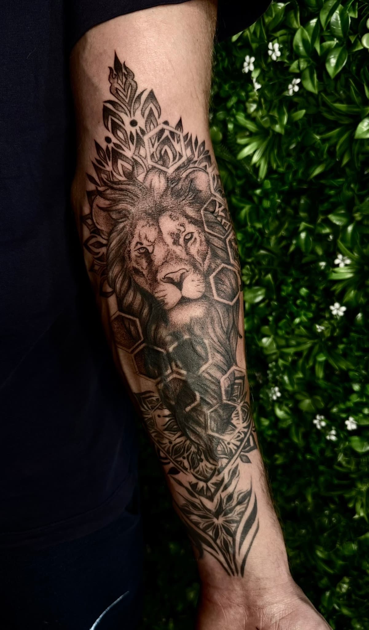 Zwart-wit tattoo van een leeuwenkop met geometrische en mandala patronen.