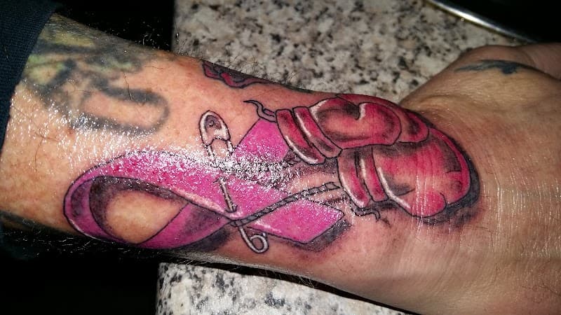 Roze lintje met veiligheidsspeld en bokshandschoenen op pols.