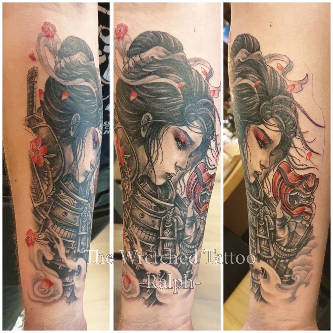 Vrouwelijke samoerai met masker en kersenbloesems op onderarm.