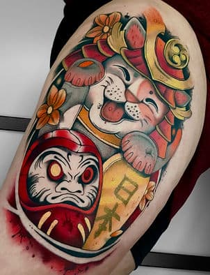 Kleurrijke Japanse Maneki-neko en Daruma tattoo op bovenbeen.