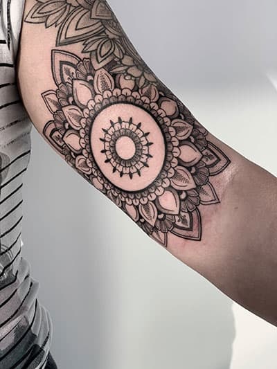 Gedetailleerde mandala tattoo met dotwork op de bovenarm.