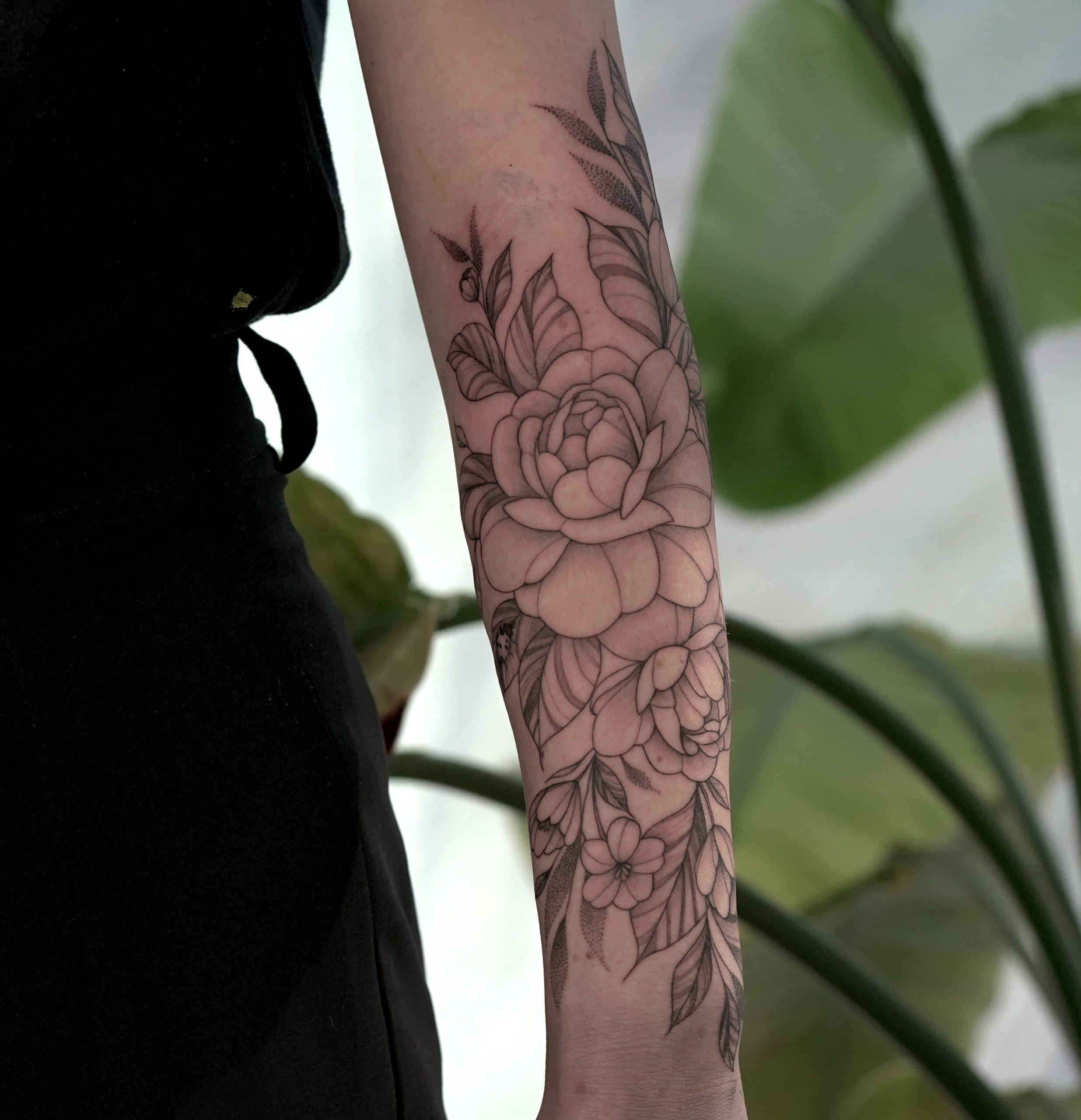 Fineline bloemen tattoo op onderarm.