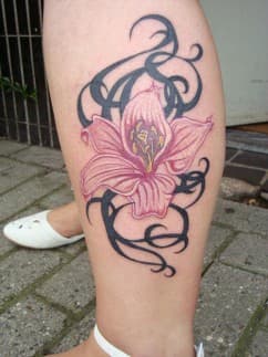 Roze lelie met zwarte tribale krullen op onderbeen.