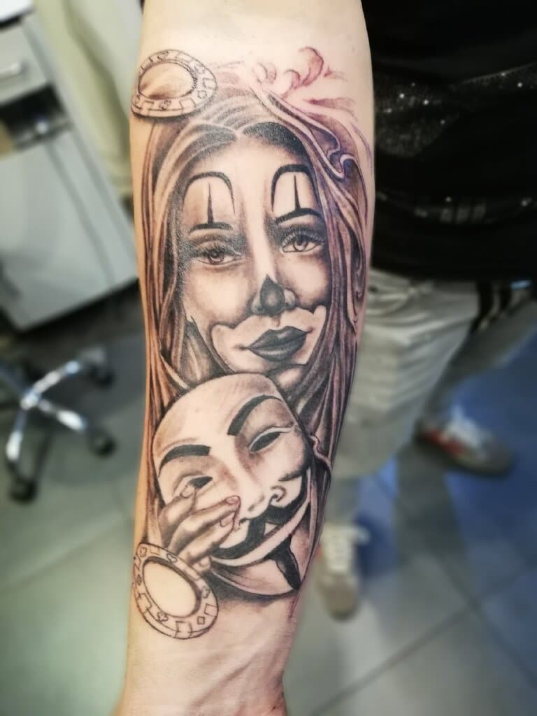 Black and grey tattoo van een vrouw met clown make-up en een Guy Fawkes masker.