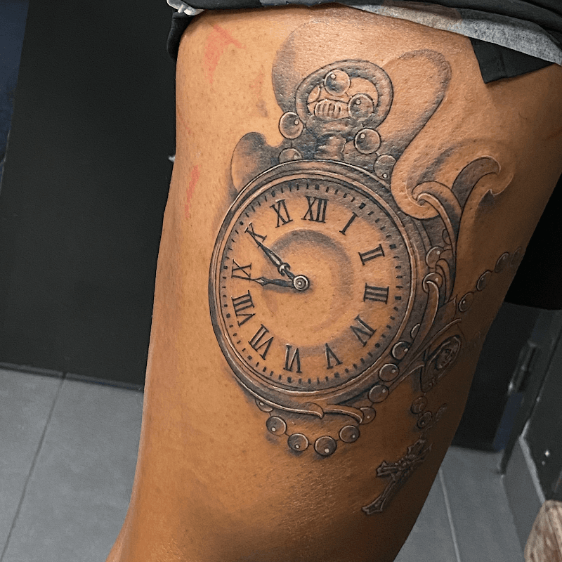 Gedetailleerde black & grey tattoo van een zakhorloge met rozenkrans en kruis.