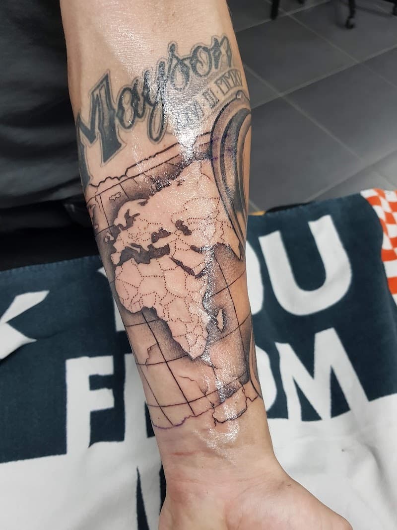 Wereldkaart met naam 'Mayson' en datum op onderarm.