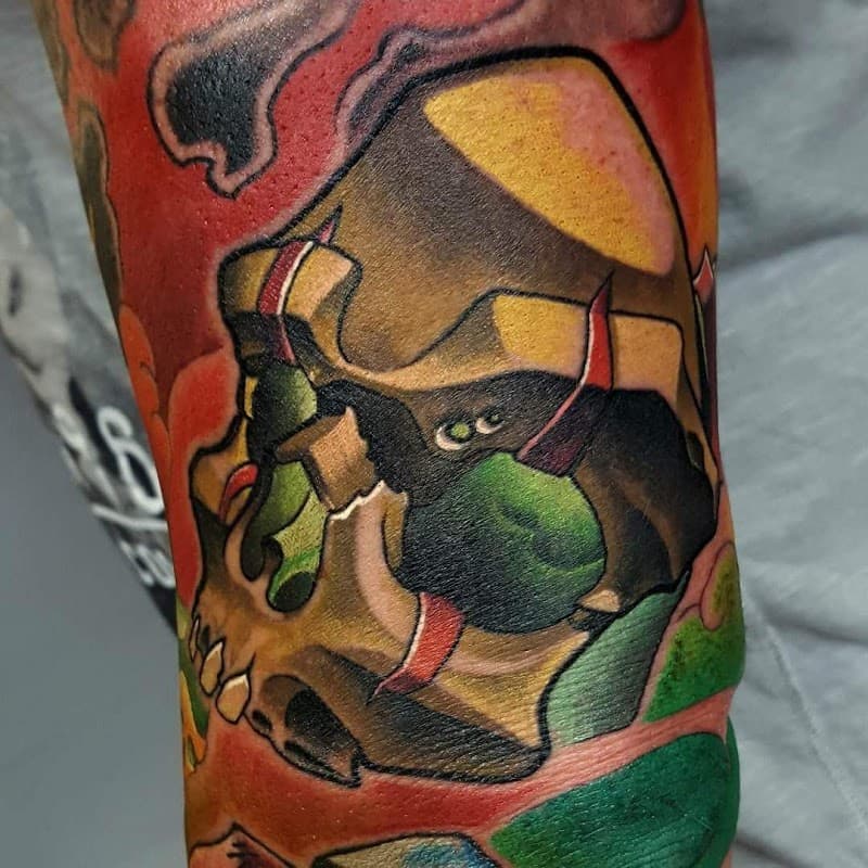 Kleurrijke neo-traditional schedel tattoo met gouden en groene tinten.