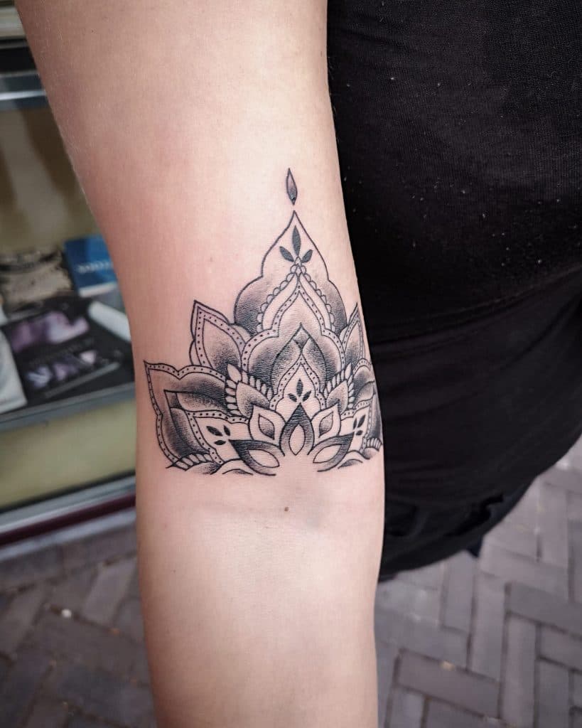 Zwart-wit mandala lotus tattoo op de bovenarm met dotwork details.