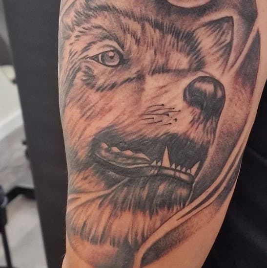 Realistische wolfskop tattoo op bovenarm.