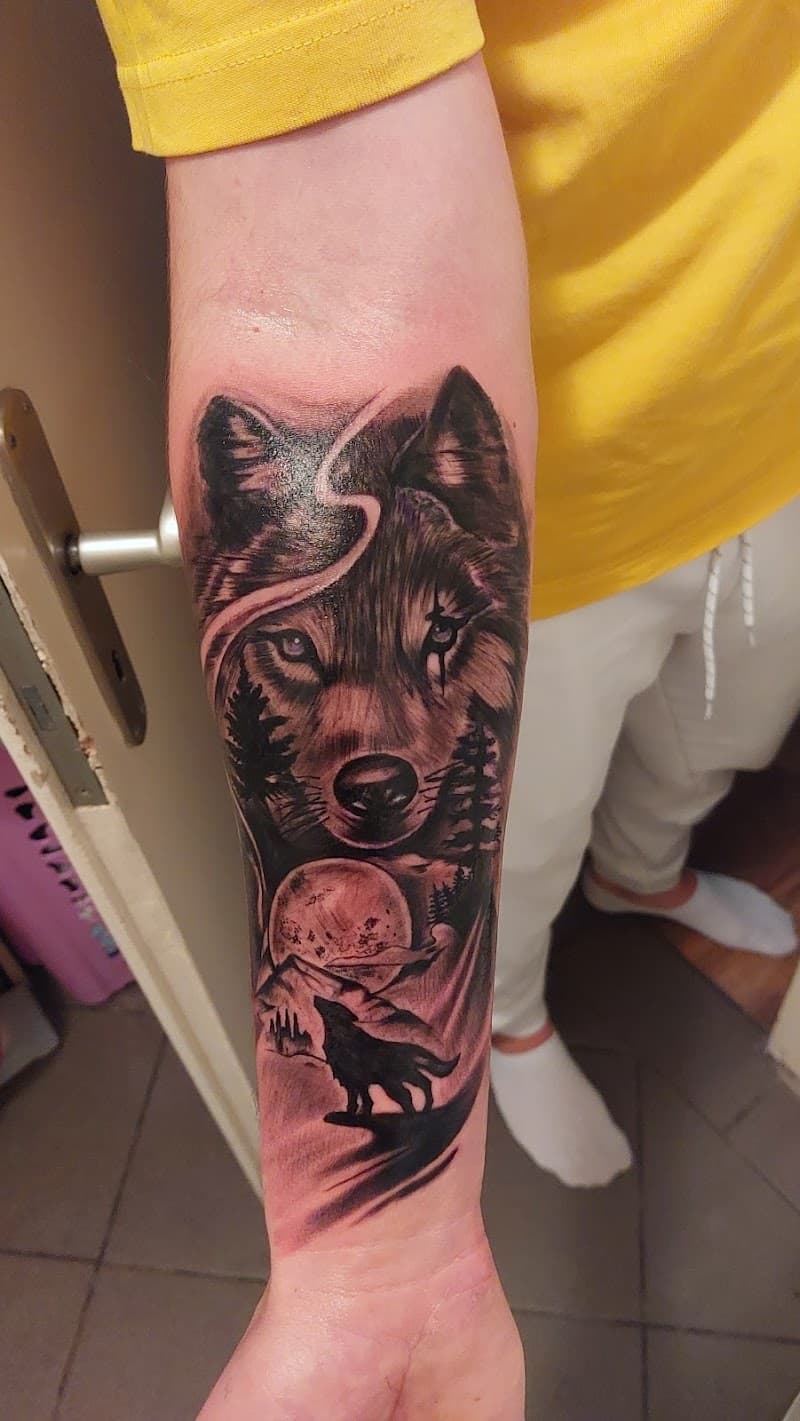 Blackwork wolf met bos en maan op onderarm.