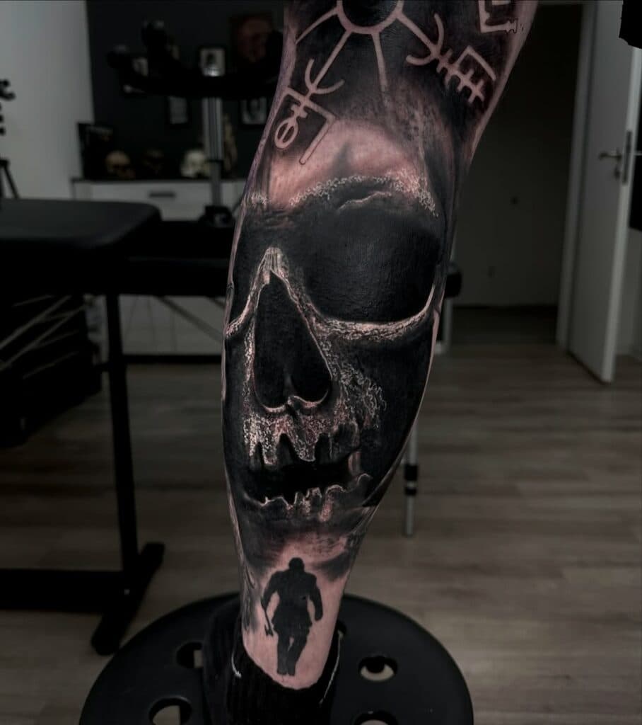 Grote schedel met runen en Kratos silhouet op onderbeen.