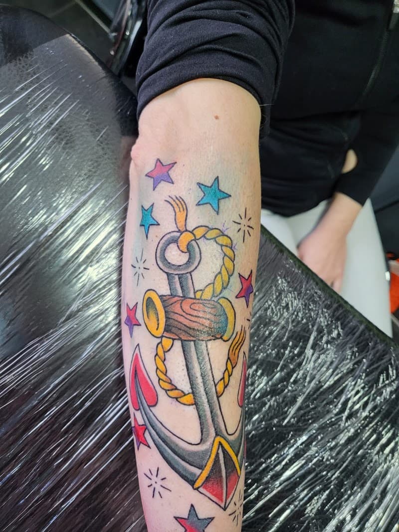 Old school anker tattoo met sterren en touw op onderarm.