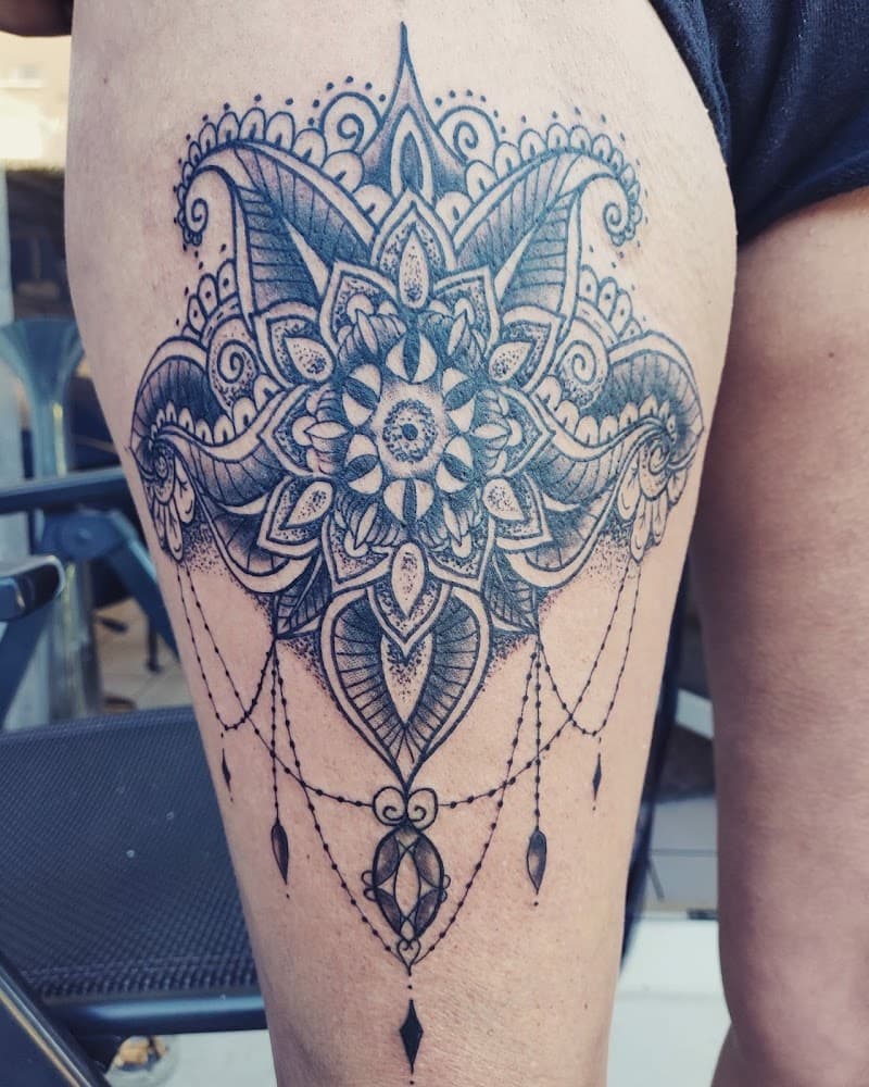 Grote mandala tattoo met dotwork en hangende sieraden op het bovenbeen.