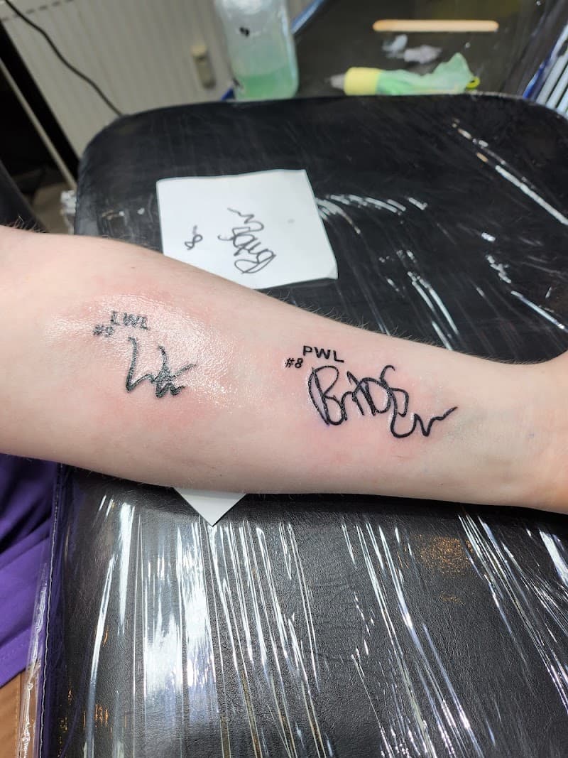 Twee handtekening tattoos met tekst 'LWL #9' en 'PWL #8' op onderarm.