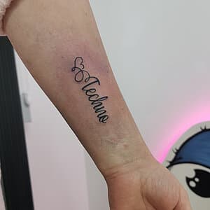 Fineline 'Techno' tekst met hartje op onderarm