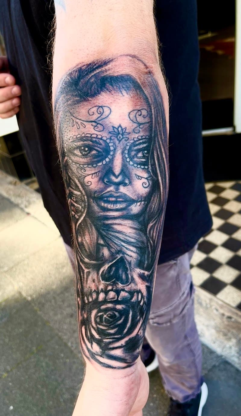 Zwart-wit tattoo van een vrouw met een suikerschedel gezicht en een roos.