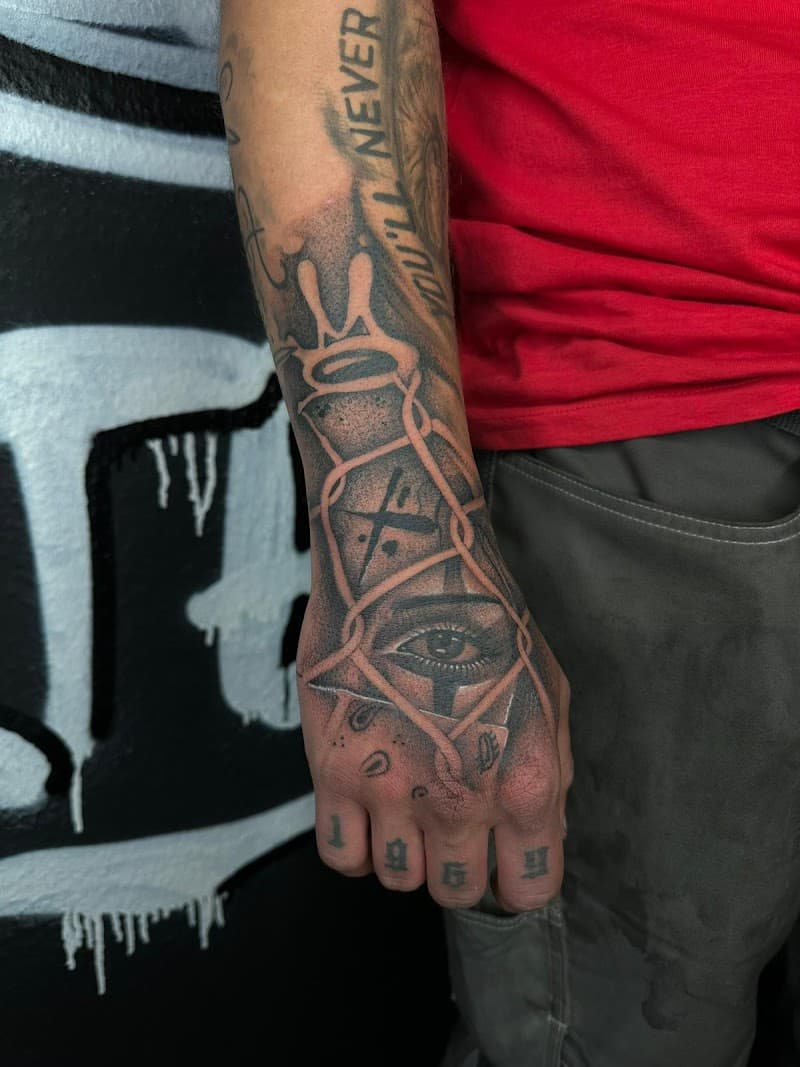 Handtattoo met oog, kroon en hekwerk, plus '1969' op vingers.