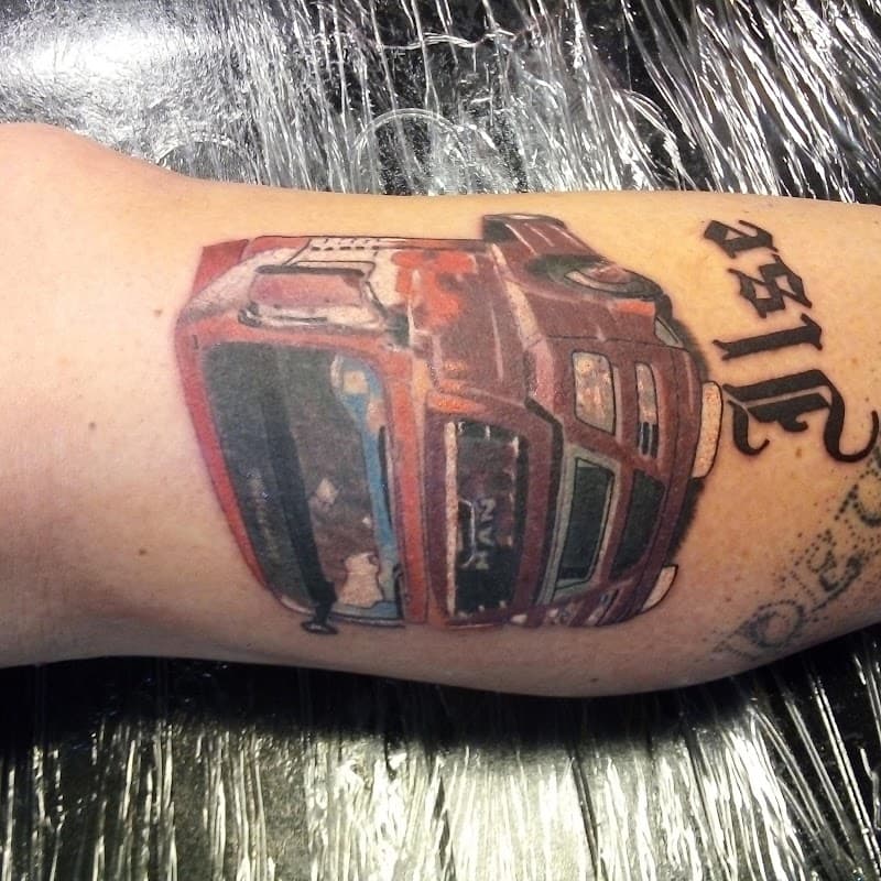 Rode MAN vrachtwagen en 'Ilse' tekst tattoo op onderbeen.