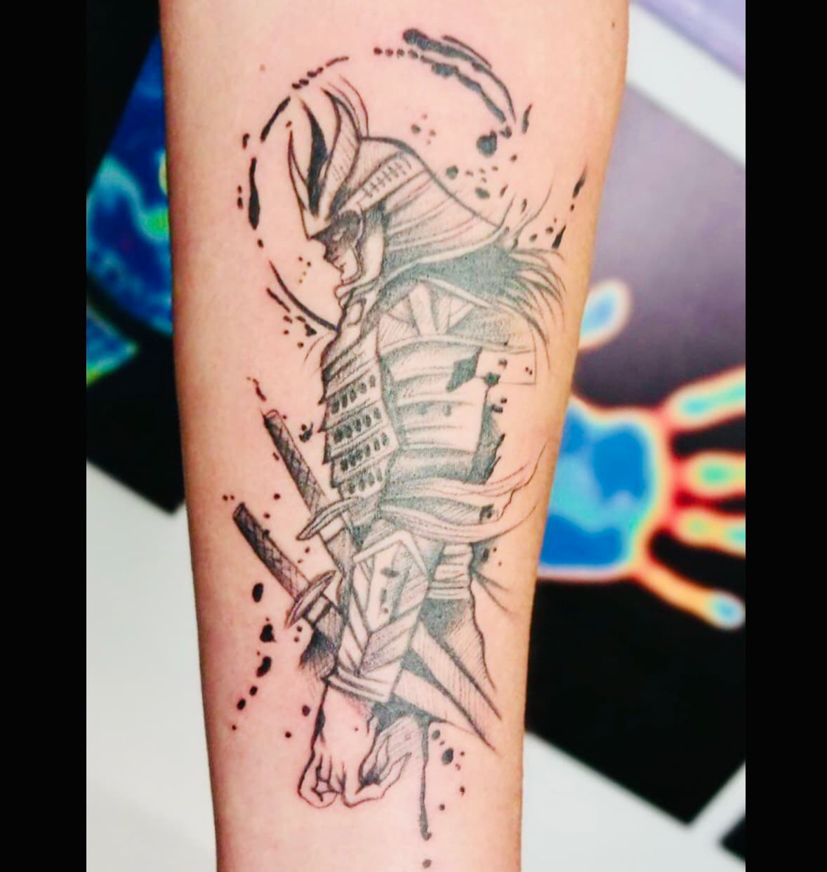 Schetsstijl samurai tattoo met inktspatten op onderarm