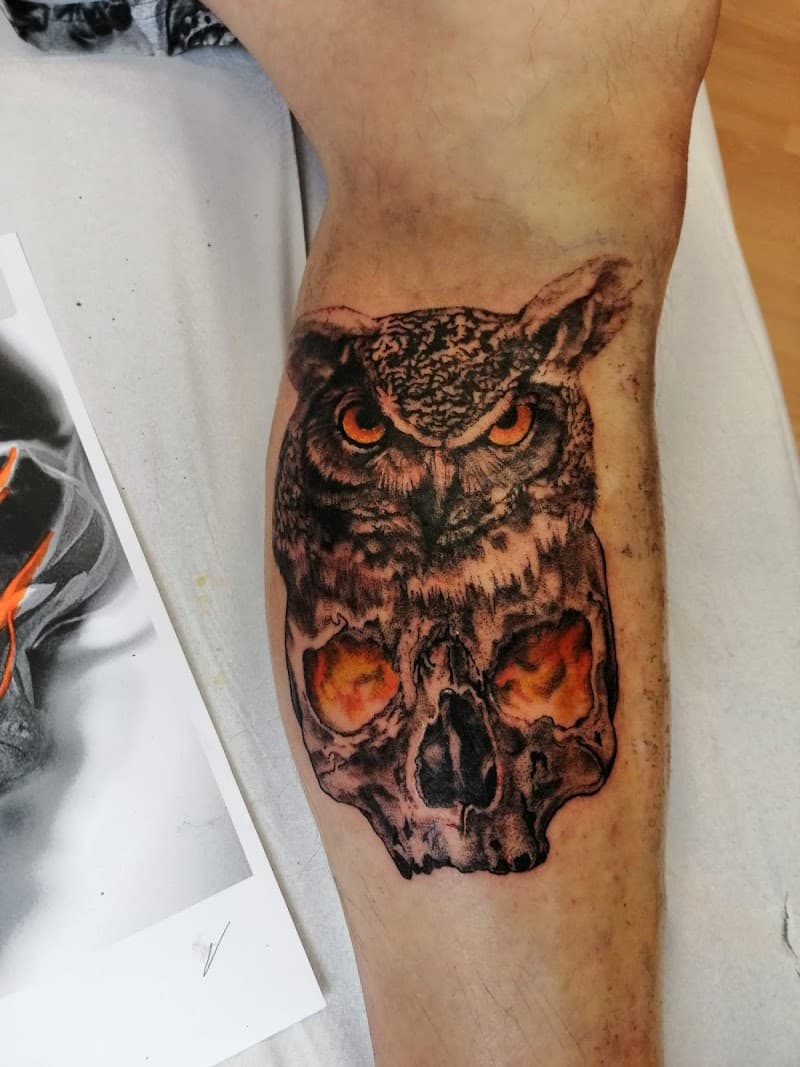 Realistische uil op schedel met vurige ogen op onderbeen.