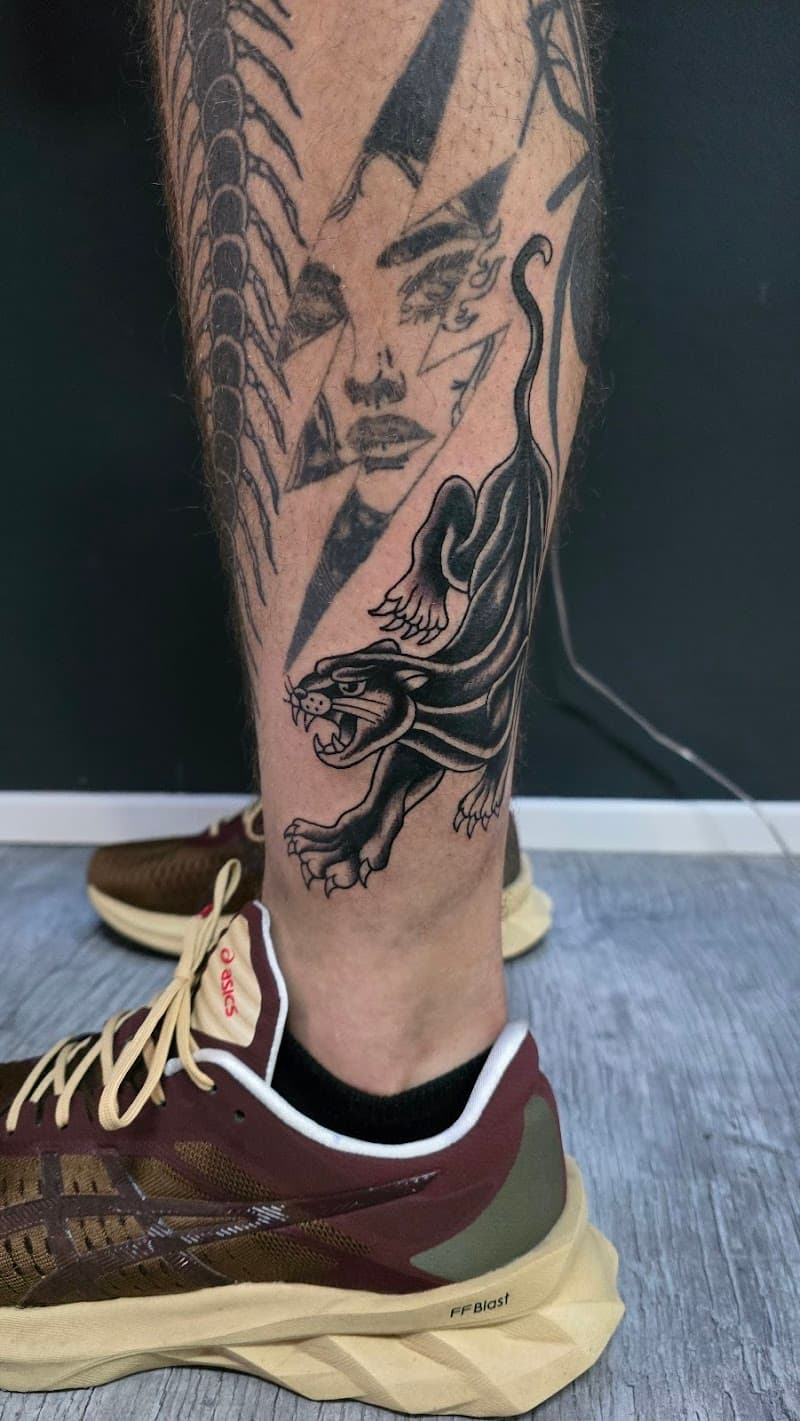 Zwarte panter tattoo in traditionele stijl op het onderbeen.