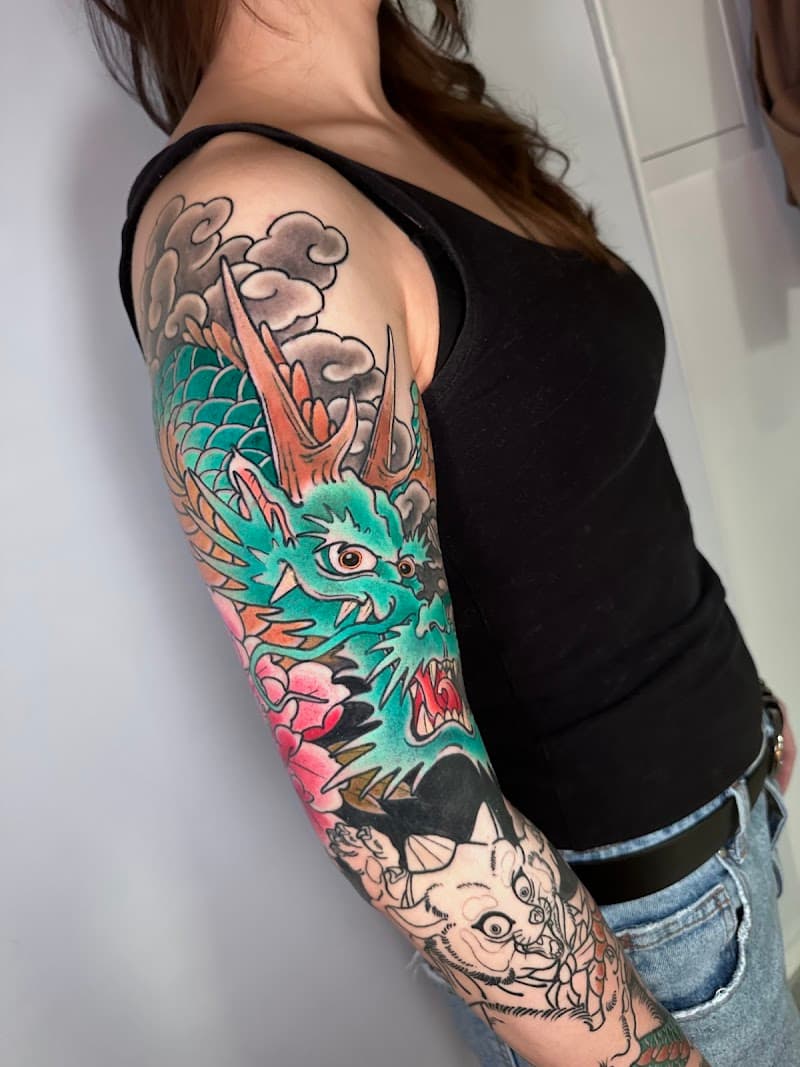 Grote Japanse draak tattoo in kleur op de bovenarm en onderarm.