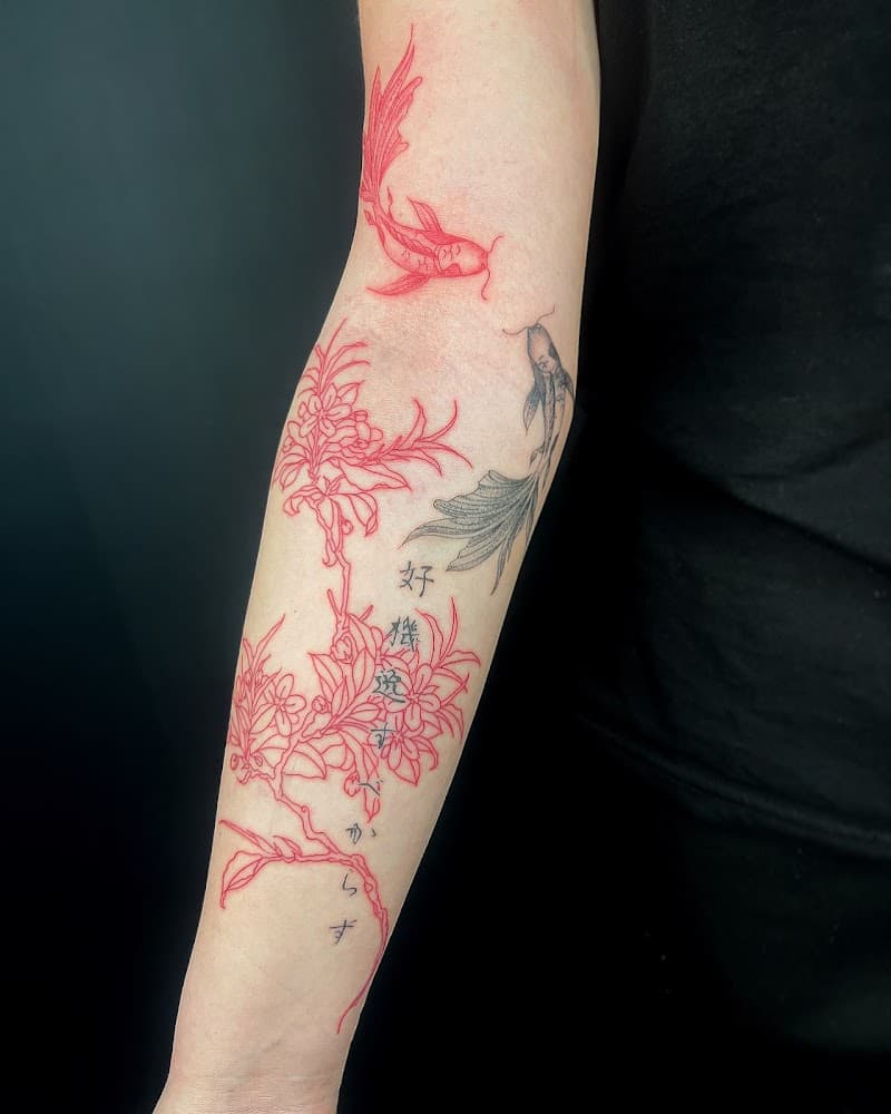 Rode en zwarte vissen met rode bloesemtak en tekst op onderarm.