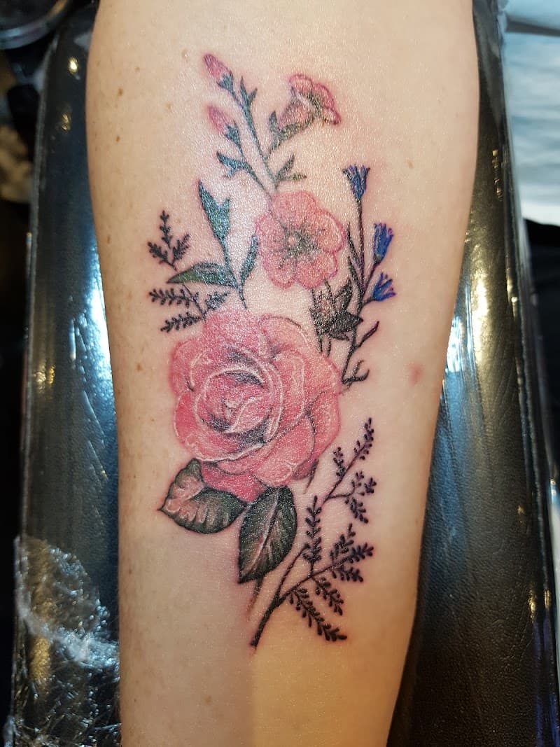 Roze roos met kleinere roze bloemen en donkere bladeren.