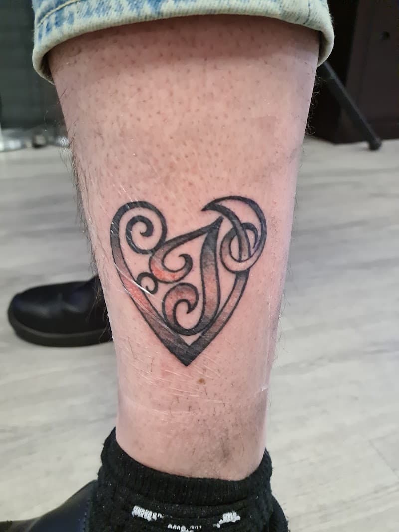 Zwart-wit hart met sierlijke krullen en de letter 'J' op het onderbeen.