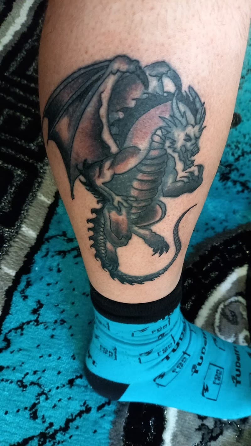 Zwart-grijze draak tattoo op het onderbeen.