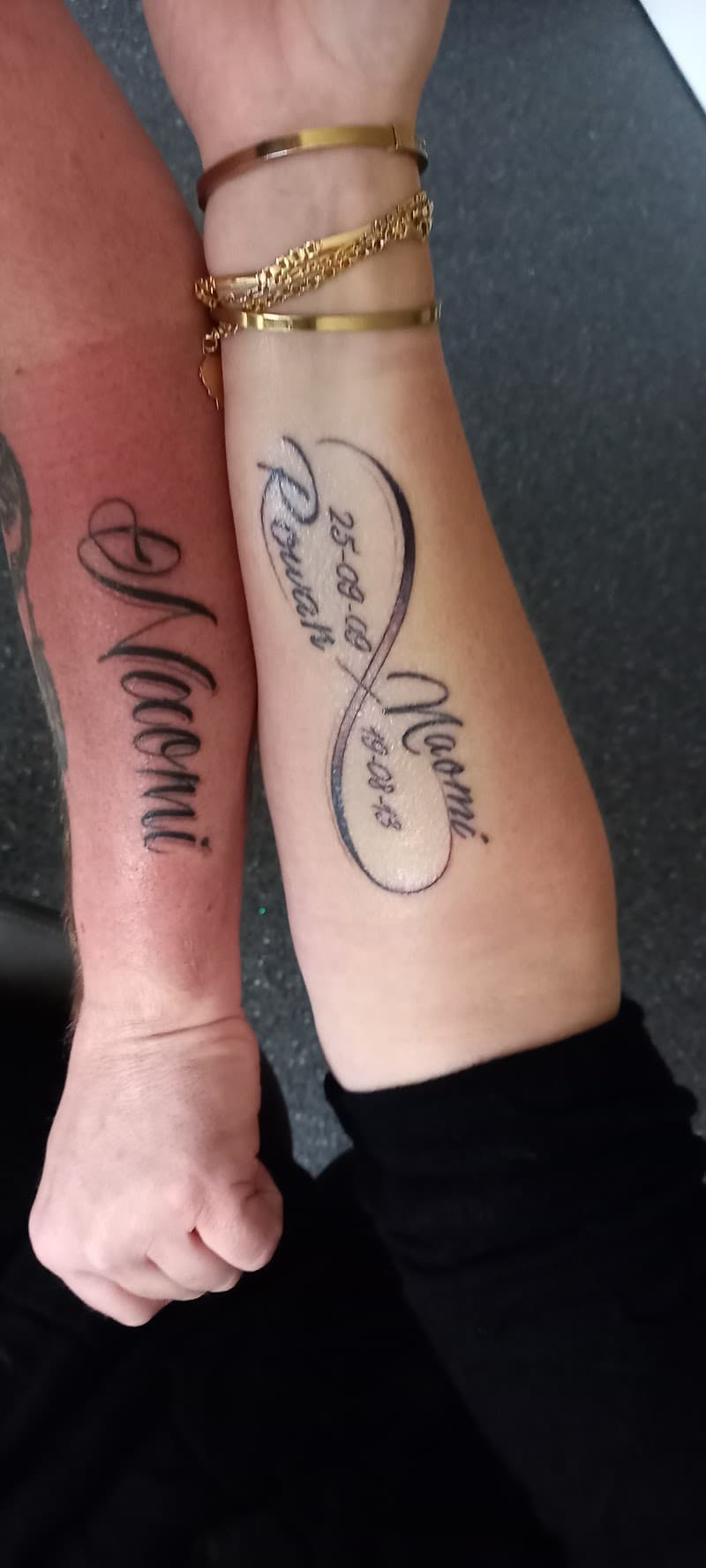 Twee onderarmen met namen en een infinity symbool met datums.