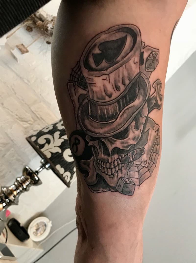 Zwart-wit tattoo van een schedel met hoge hoed, kaarten, dobbelstenen en 8-ball.