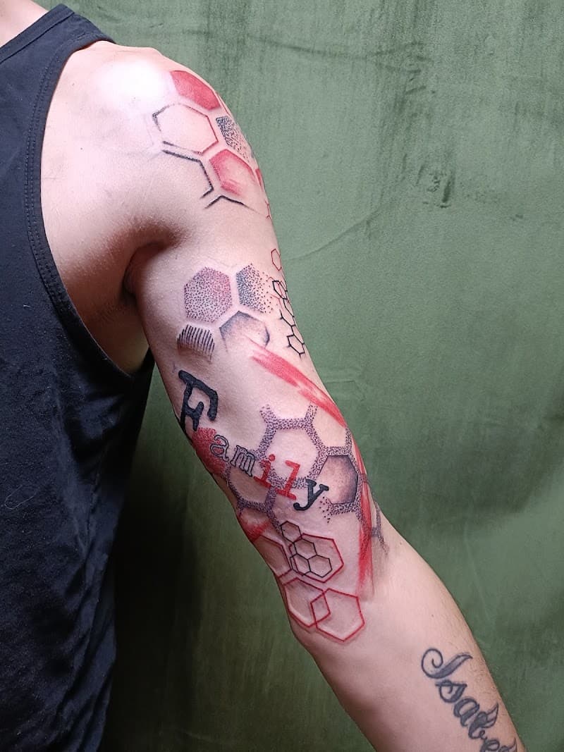 Abstracte geometrische tattoo met 'Family' tekst en rode accenten op arm.