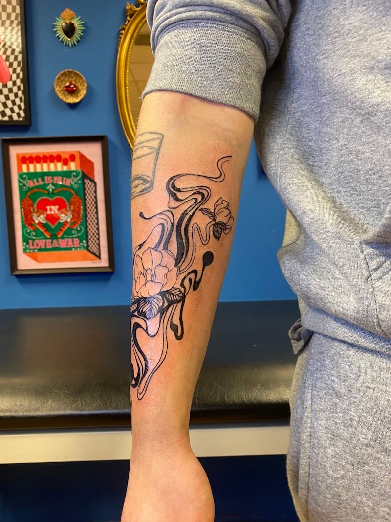 Zwart-wit tattoo van bloemen gecombineerd met vloeiende, abstracte lijnen.