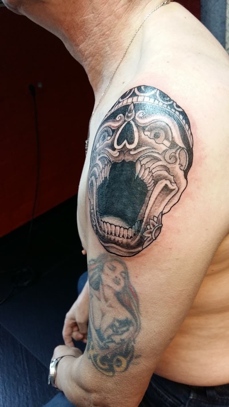 Gedetailleerde zwart-wit schedel met open mond en decoraties op de bovenarm.