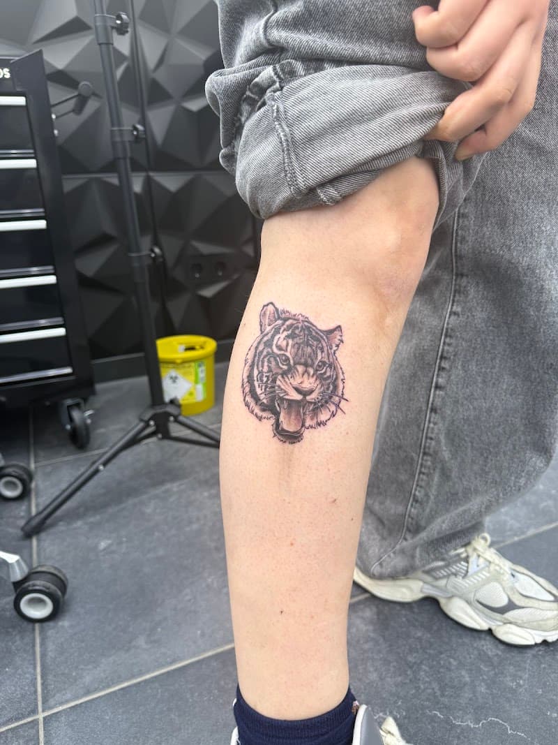Fineline tijgerkop tattoo op het onderbeen.