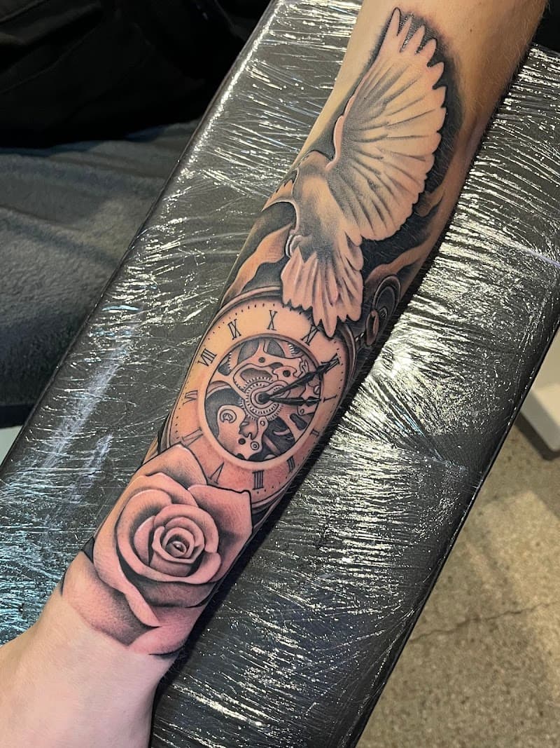 Realistische duif, klok en roos tattoo op onderarm.