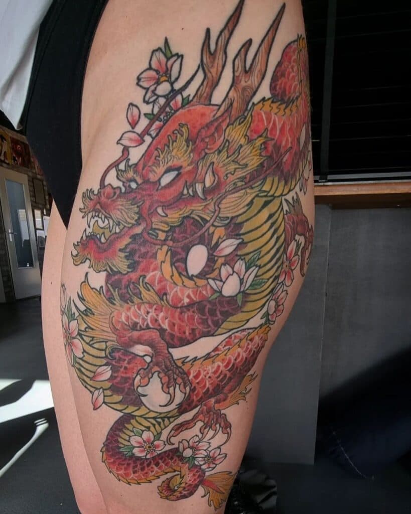Grote Japanse draak tattoo in kleur met kersenbloesems op het bovenbeen.
