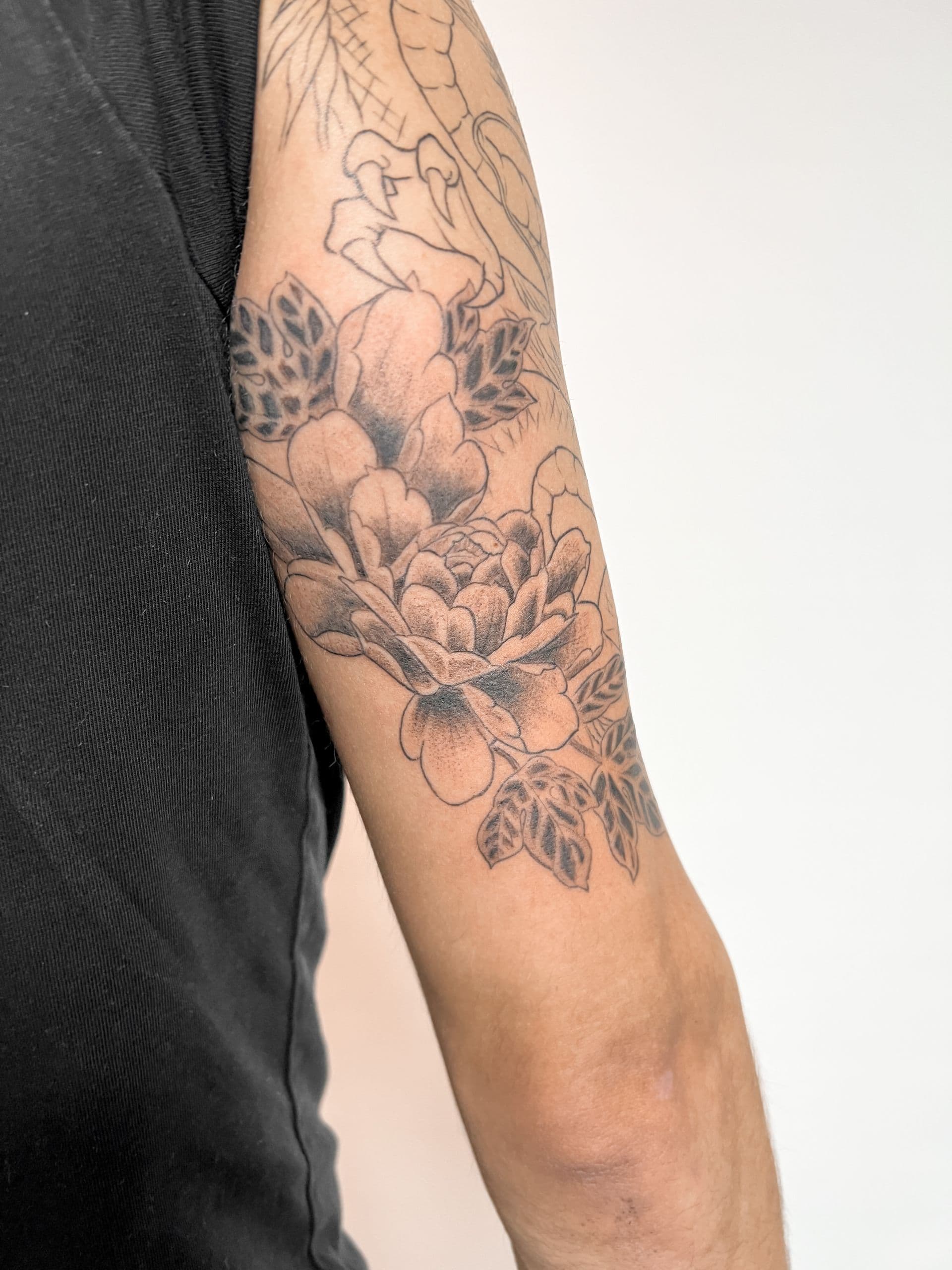 Zwart-wit bloemen tattoo op bovenarm, deels genezen.