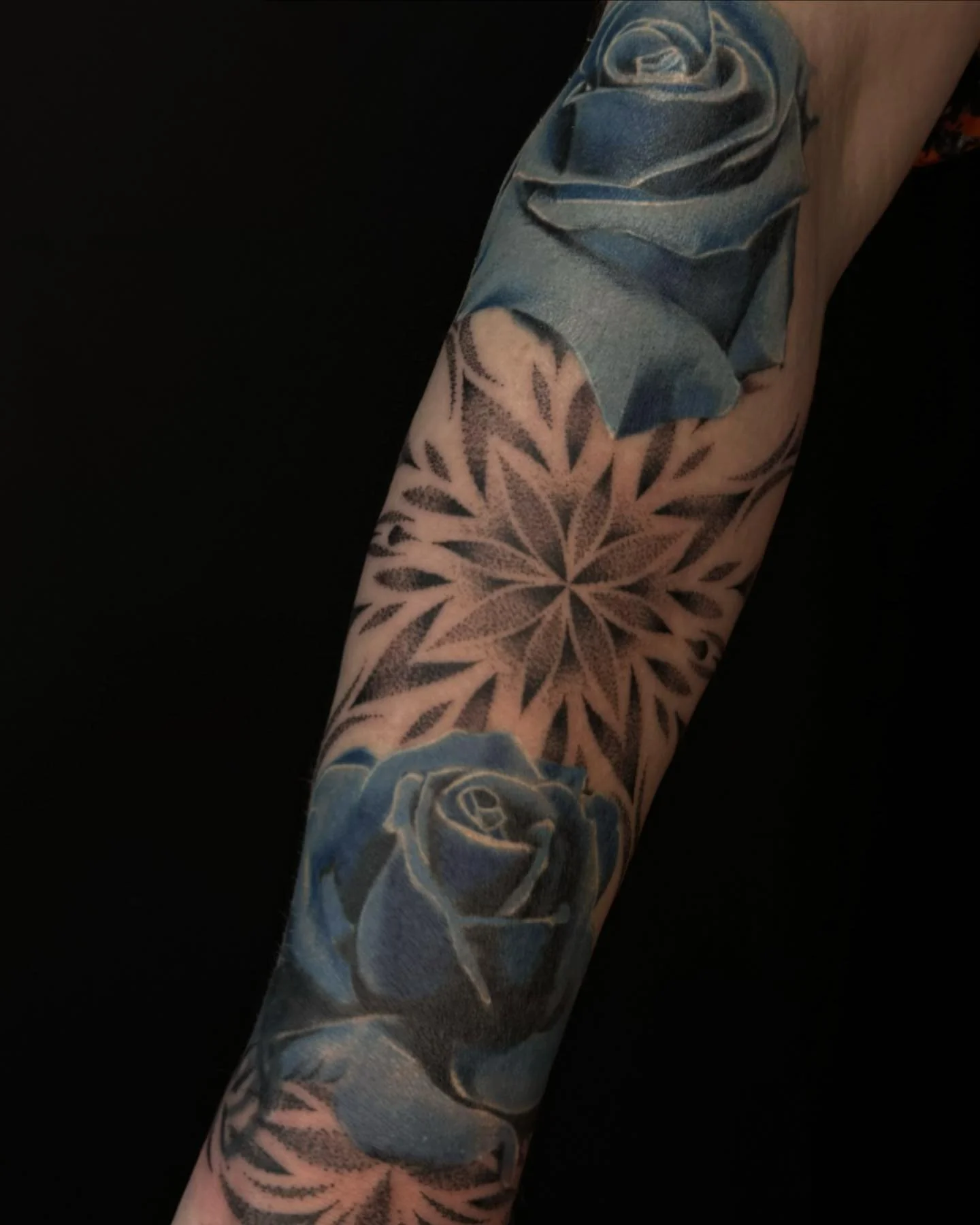 Blauwe rozen en geometrische mandala op onderarm.