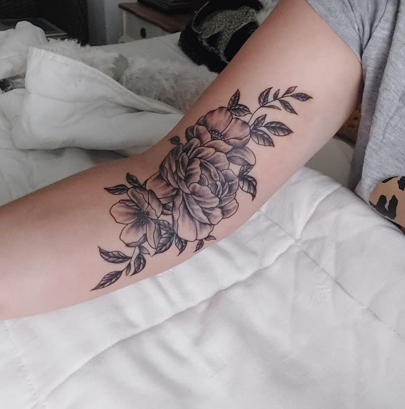 Zwart-wit bloemen tattoo op de binnenkant van de bovenarm.