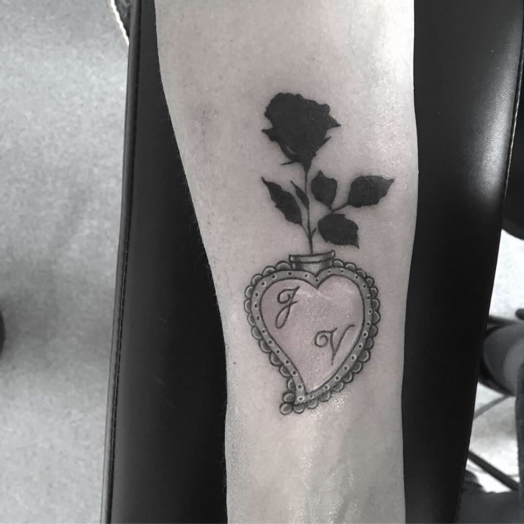 Blackwork roos in een hartvormige vaas met initialen 'JV'.