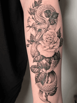 Gedetailleerde zwart-wit tattoo van een slang gewikkeld om een roos met bladeren.