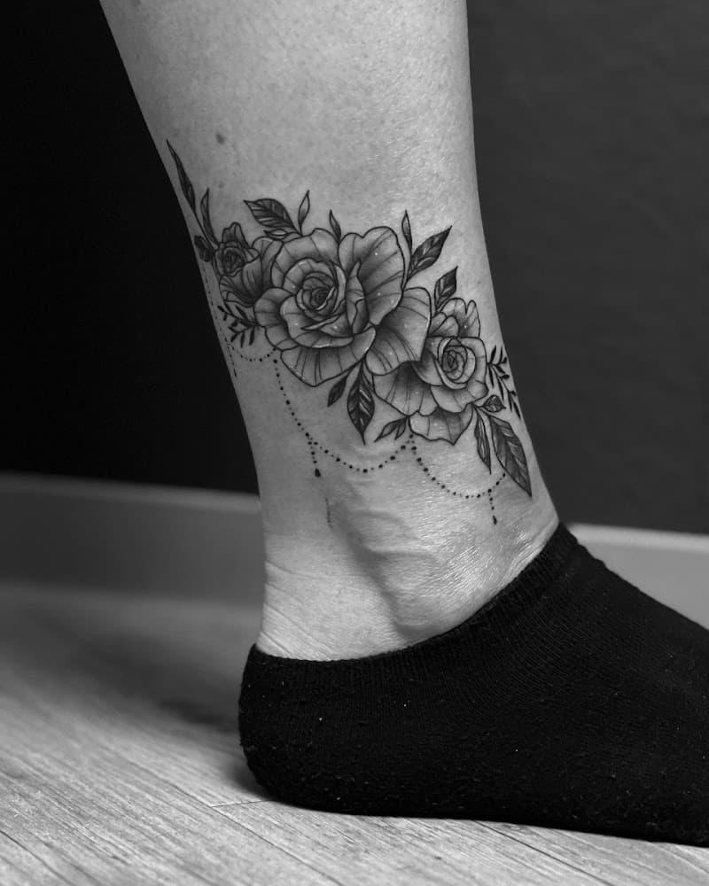 Zwart-wit rozen tattoo met dotwork parels op de enkel.