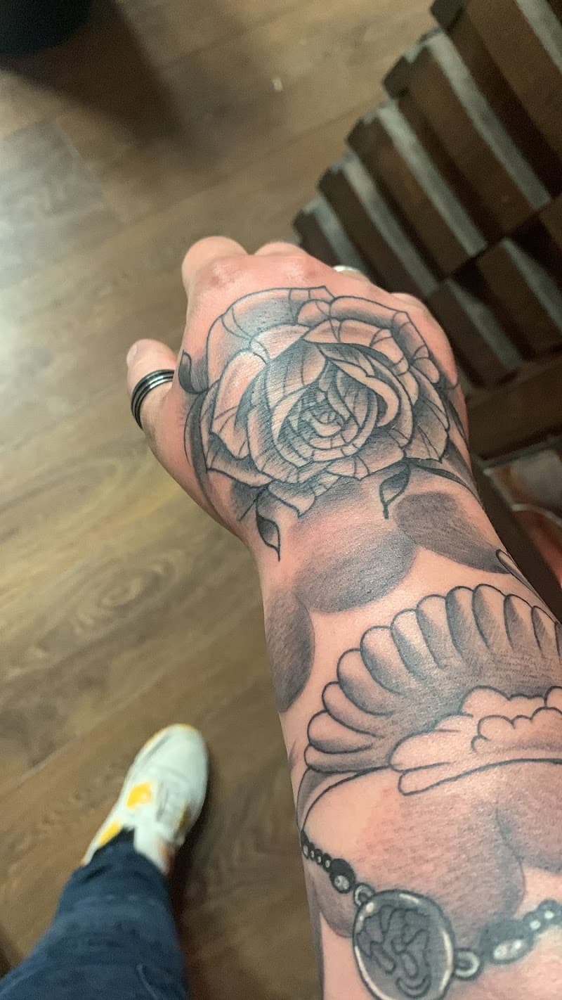 Zwart-wit roos op hand en schelp met ketting op onderarm.