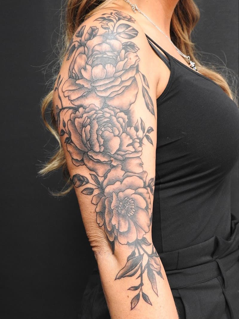 Grote zwart-wit bloemen tattoo op de bovenarm.