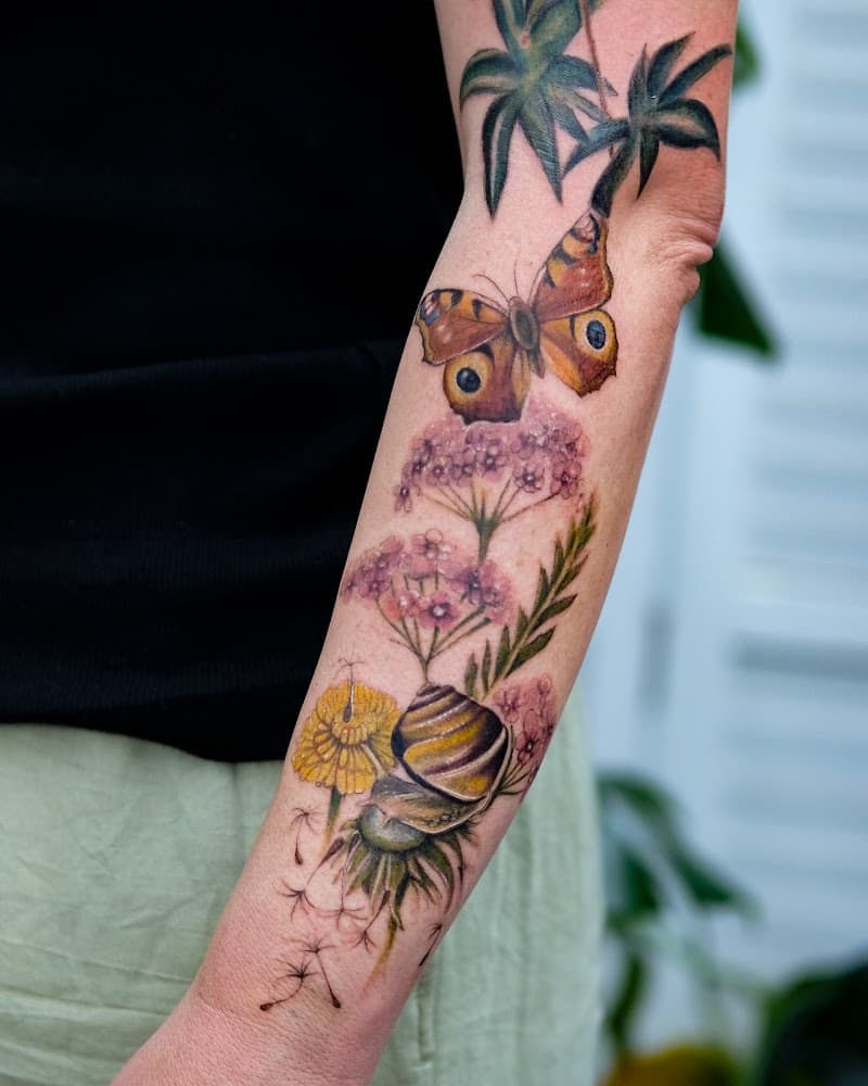 Realistische vlinder, slak en bloemen op onderarm.